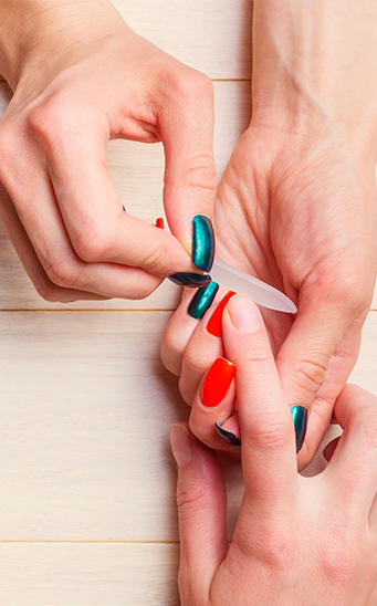 Manicurista quita cutículas en uñas femeninas